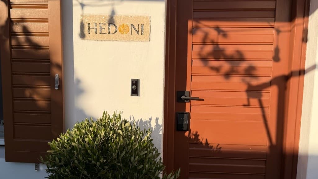 Hedoni mosaic sign and entrance door with olive tree in Mykonos Town