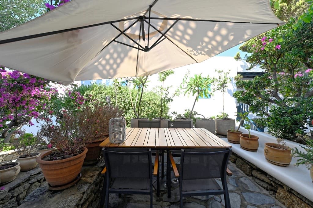 Private courtyard with outdoor dining table, umbrella and bougainvillea at Hedoni